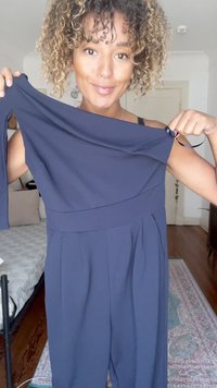 Tamsiai mėlynas off-shoulder šokinėlis su ilgomis rankovėmis, prigludusia liemene ir plačiomis kojomis, demonstruojantis minkštą faktūrą ir elegantišką dizainą.