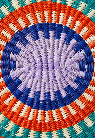 Panier tressé rond présentant des cercles concentriques vibrants en turquoise, orange, blanc, violet et bleu, fabriqué à partir de fibres naturelles.