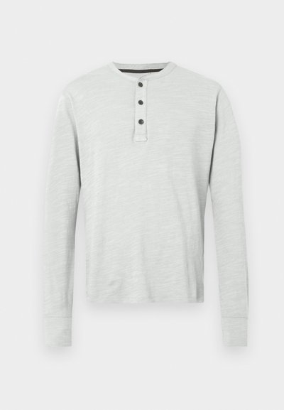 Jasnoszara, długosleeve'owa koszulka henley z miękkiego materiału, z czterema guzikami przy plisce i ściągaczami na rękawach. Gładka tekstura.