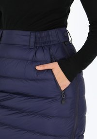 Gevoerde rok in donker marineblauw, met een elastische tailleband en knoop, zijzakken en een gequiltde textuur met horizontale stiksel.