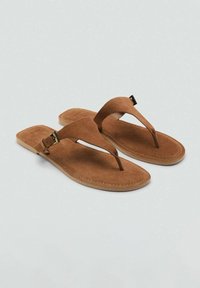 Sandale din suede maro, cu brida ajustabilă și talpă plată, având un design simplu și detalii cusute pe margini.
