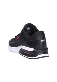 Baskets de sport noires avec une tige texturée, des accents rouges, une semelle blanche et un élément de coussin d'air visible au niveau du talon.