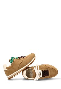 Zapatillas de ante en color marrón claro con un acabado texturizado. Presentan detalles en crema, cordones marrones y adornos verdes en los cordones. Suela de goma gruesa.