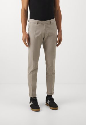 Light beige chinos with a slim fit, made of soft fabric. Features side pockets and stitched front seams. Matched with black sneakers.