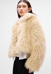 Crème nep bont jas met een fluffy, gestructureerde afwerking en oversized mouwen, met een cropped ontwerp en brede kraag.