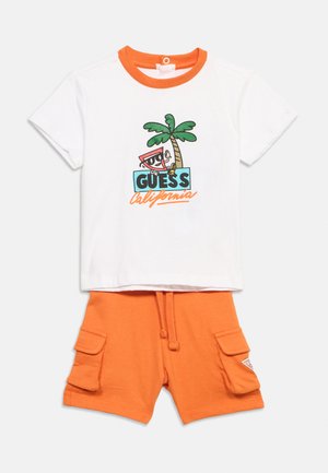 T-shirt blanc pour tout-petit avec col orange et motif de palmier, associé à un short cargo orange avec poches latérales et taille à cordon.