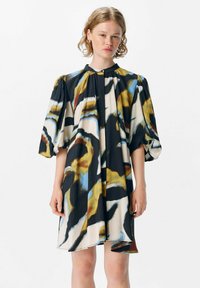 Robe à manches courtes, longueur genoux, avec un motif abstrait coloré présentant du noir, du bleu et du jaune sur un fond crème ; tissu doux et coupe décontractée.