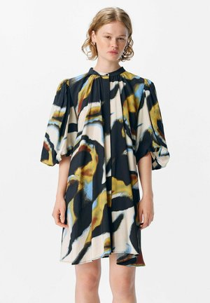 Robe à manches courtes, longueur genoux, avec un motif abstrait coloré présentant du noir, du bleu et du jaune sur un fond crème ; tissu doux et coupe décontractée.
