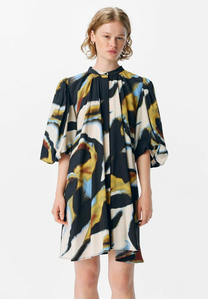 Vestido de manga corta y largo hasta la rodilla en un colorido patrón abstracto que presenta negro, azul y amarillo sobre una base color crema; fabricado en tejido suave y con un corte relajado.