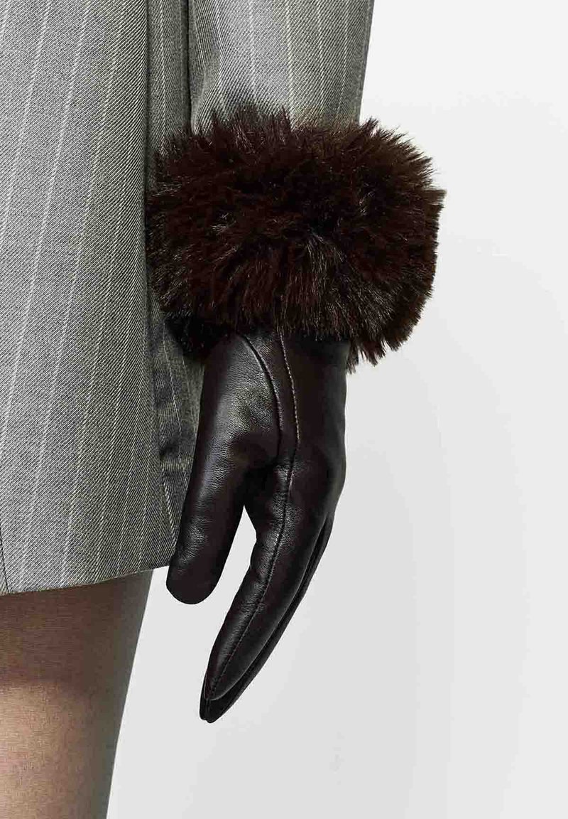 Hnedá kožená rukavica s mäkkým, tmavým kožúškom na manžete. Rukavica je elegantná, priliehavá a má mierne špicatý prst.