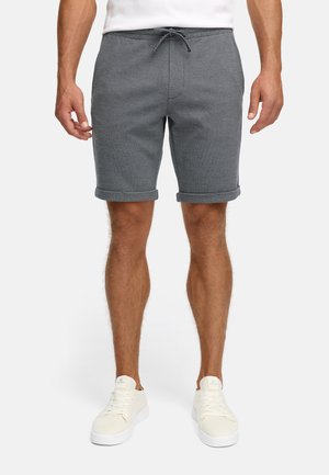 Herre grå strikkede shorts med oppbrettede kanter, med elastisk liv og snor. Kombinert med hvite snørebåndsneakers.