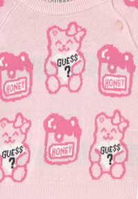 Vaaleanpunainen neulepusero, jossa on sarjakuvakarhuja ja hunajapurkkeja tummanpunaisina kontrasteina. Karhuilla on leikkisiä ilmeitä ja tekstikuvioita.