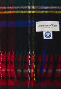 Skotsk uld-halstørklæde i mørke nuancer med røde, grønne, blå og gule accenter. Har frynset ender og et mærke, der læser "Johnstons of Elgin."