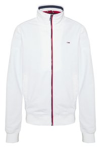 Chaqueta blanca con cremallera y cuello alto, con detalles en rojo y azul marino, bolsillos delanteros y cintura y puños acanalados. Logo en el lado izquierdo del pecho.