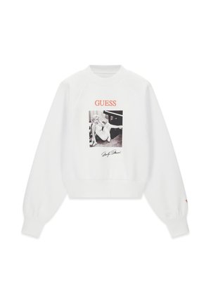 Hvid langærmet sweatshirt med et sort-hvidt foto af en kvinde, der sidder ved et klaver, rød "GUESS" tekst og en sort underskrift nedenfor.