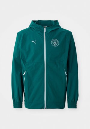 Teal let jakke med hætte, frontlynlås, elastiske manchetter og sidelommer. Har Manchester City-logo og kontrasterende lynlås.