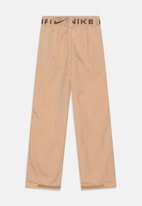 Beige kalhoty Nike s texturovaným povrchem, elastickým pasem s černým logem a širokými nohavicemi. Lemování je mírně zúžené.