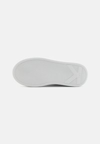 Vit sneakersula med ett texturerat vågmönster. Har en framträdande logotyp och en slät, rundad kant. Ren, minimalistisk design.