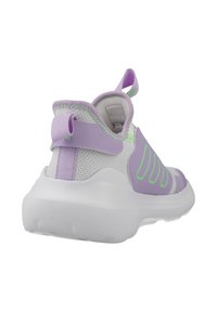 Zapatilla de malla morada y blanca con un talón acolchado, acentos verdes y una suela blanca gruesa. Cuenta con un lazo para facilitar su puesta.