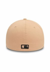 Gorra de béisbol ajustada color beige con textura suave, visera curvada y un pequeño parche de logo bordado en negro en la parte posterior.