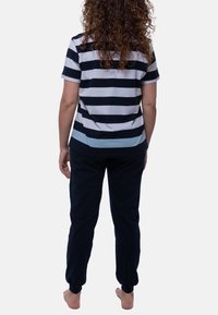 Raidoitu lyhythihainen paita tummansinisessä ja valkoisessa, vaaleansinisen korostuksen kanssa, yhdistettynä tummansinisiin housuihin. Rentoa istuvuutta pehmeästä kankaasta ja joustavista hihoista.