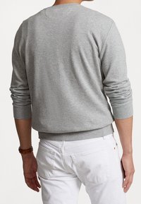 Grauer Baumwollpullover mit Rundhalsausschnitt, gerippten Bündchen und Saum, leicht lockerer Schnitt, getragen über weißen Hosen und zeigt eine glatte Textur.