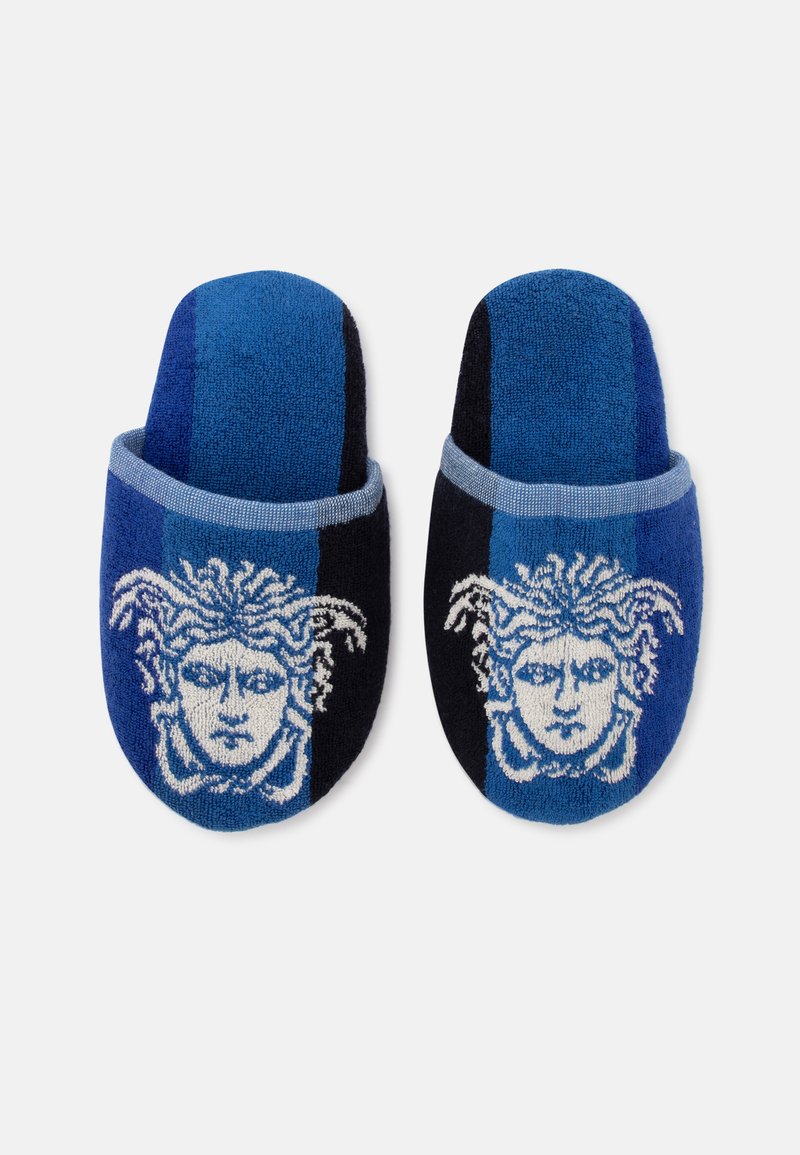 Paar blaue und schwarze Slipper mit einem weißen Medusa-Kopf-Design auf jedem vorderen oberen Bereich.