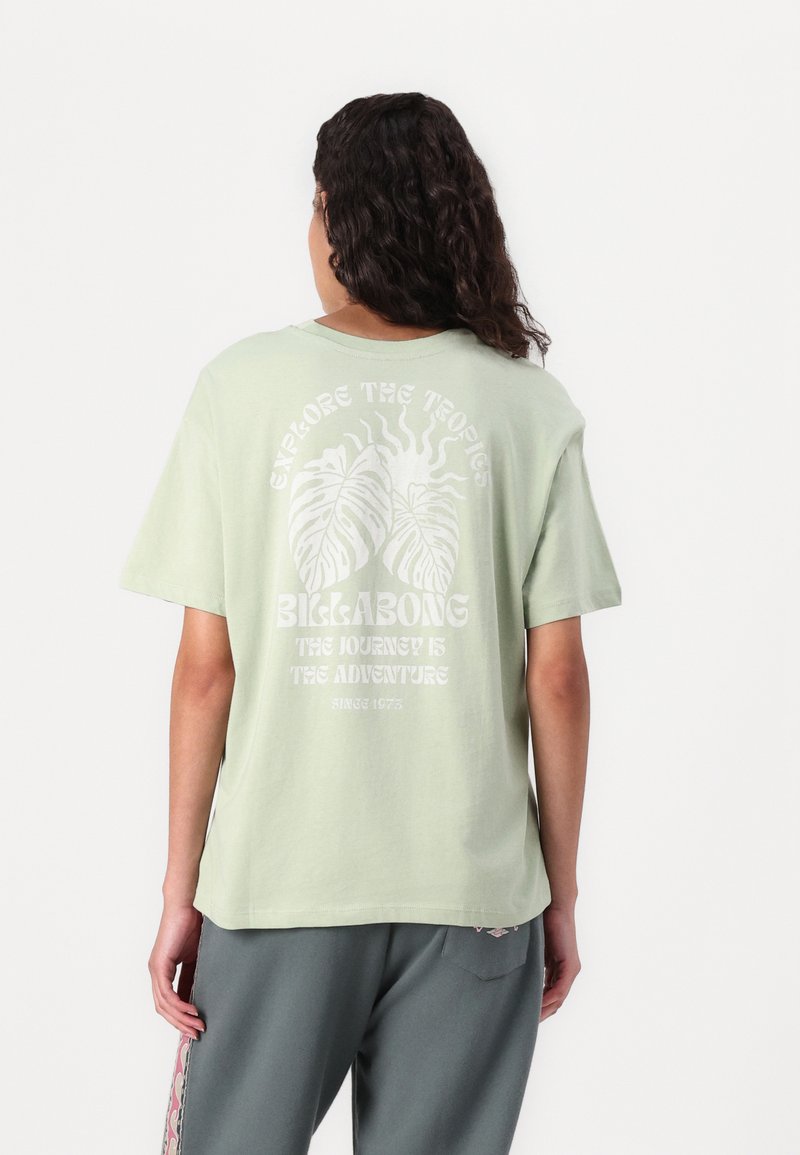 Light green cotton t-shirt with short sleeves. Graphic print on back featuring tropical leaves and text in white. Relaxed fit.