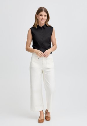 Chemise sans manches noire à boutons et pantalon large blanc. Ballerines marron. Tissu lisse et design structuré avec un col classique.