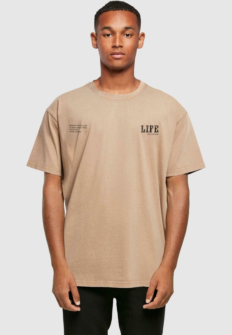 Beige, oversized, pamut póló rövid ujjakkal, bal mellen és oldalon nyomtatott szöveggel. Kerek nyakú, laza szabású.