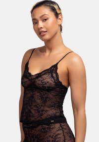 Zwarte kanten camisole met verstelbare spaghettibandjes, bloemmotief, geschulpte randen en een aansluitend ontwerp met een kanten afwerking aan de zoom.