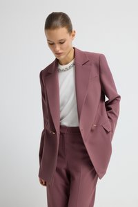 Maatwerk twee-delig kostuum in mauve, met een gestructureerde blazer met notch revers en een sluiting met twee knopen, en bijpassende slim-fit broek.