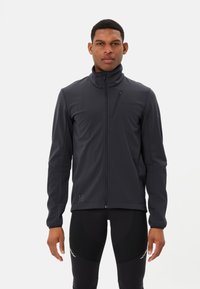 Giacca nera da uomo con zip realizzata in tessuto liscio e elasticizzato; presenta un colletto alto, tasca sul petto con zip e un branding minimale.