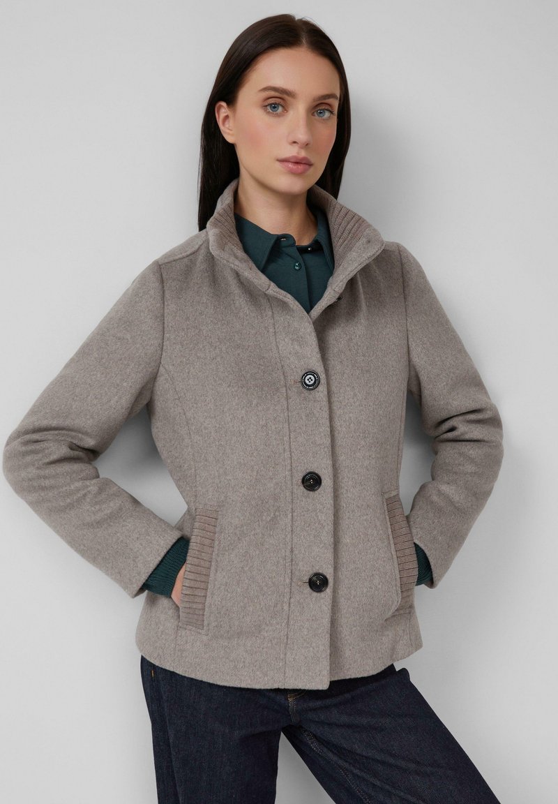 Veste en mélange de laine gris clair avec un col montant, quatre boutons noirs et poches latérales côtelées. Présente une coupe structurée et une texture douce.