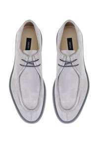 Chaussures en suède gris au toucher lisse, dotées de deux fines lacets, d'une forme de bout arrondi et d'une semelle en caoutchouc sombre contrastante.