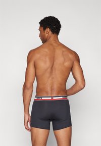 Donkergrijze boxershorts met een aangesloten ontwerp, met een meerkleurige tailleband. De tailleband heeft een logo en kleuraccenten in rood en blauw.