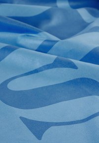 Tessuto blu con tonalità diverse, caratterizzato da motivi e trame astratte. La superficie appare liscia e leggermente lucida.
