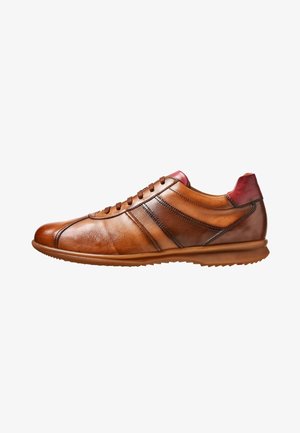 Brauner Ledersneaker mit kontrastierenden roten Akzenten, schlankem Design, runder Spitze, flacher Gummisohle und sichtbaren Nahtdetails.
