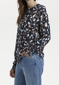 Blusa button-up a maniche lunghe con uno sfondo blu navy e un motivo astratto multicolore in marrone, crema e azzurro chiaro. Tessuto morbido.