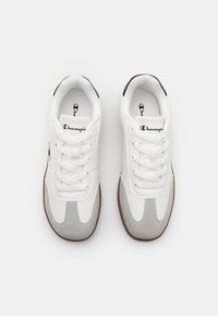 White sneakers with gray and black accents, featuring padded tongues, lace closures, and a textured rubber sole. Designed with sleek lines.