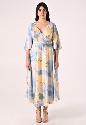 Abito lungo a fantasia floreale in tessuto morbido giallo e blu con design a incrocio e maniche a campana, caratterizzato da un leggero riflesso e da una silhouette fluida.