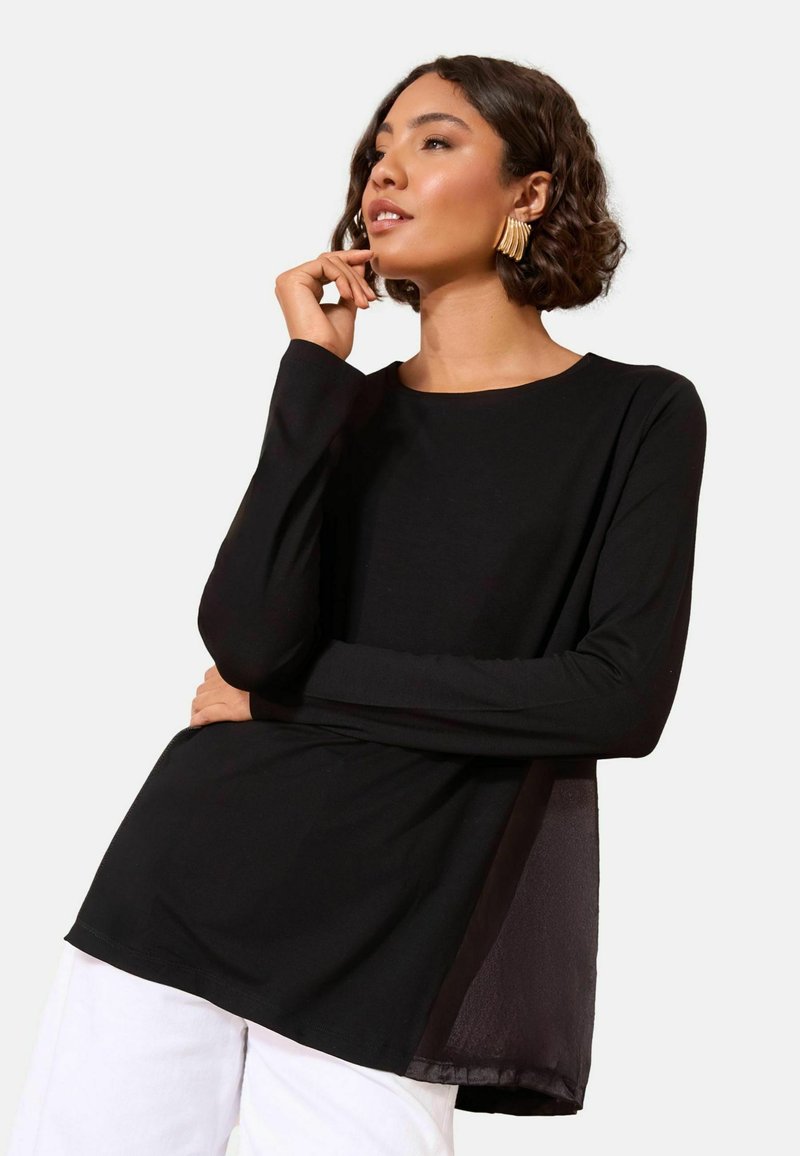Schwarzes Langarmshirt mit rundem Halsausschnitt, das ein durchsichtiges Seitenpanel und eine lässige Passform aufweist. Der Stoff wirkt weich mit einer glatten Textur.