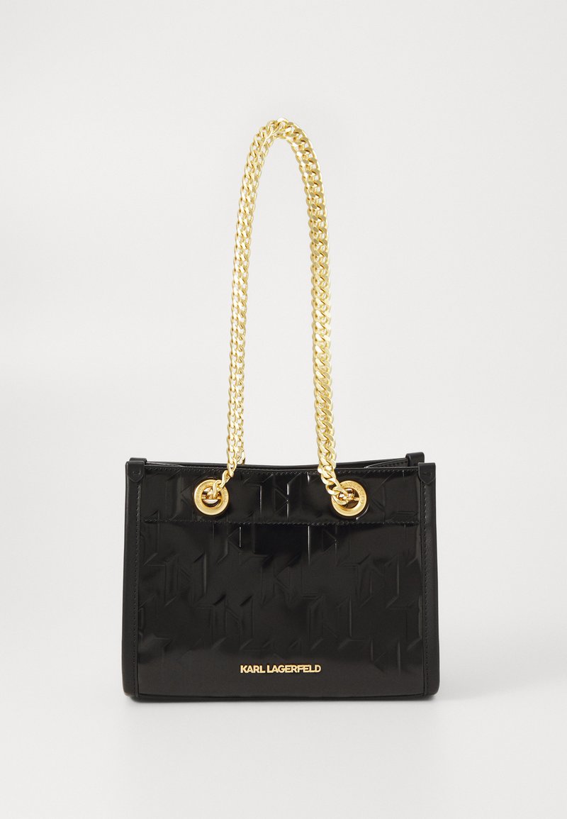 Black handbag made of glossy material, featuring a geometric pattern, gold chain handles, and a gold logo at the bottom. Minimalistic design.