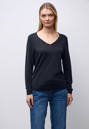 Maglione a maniche lunghe blu navy con scollo a V, realizzato in tessuto morbido, con polsini e orlo a coste, abbinato a jeans blu.
