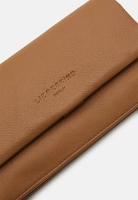 Braune Leder Brieftasche mit strukturierter Oberfläche, ausgestattet mit einem subtil geprägten Logo und einem Klappdesign. Genähte Kanten sichtbar.