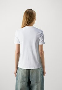 Witte katoenen t-shirt met korte mouwen en een ronde hals, met een gladde textuur en een ontspannen pasvorm, gedragen met lichte denim broek.
