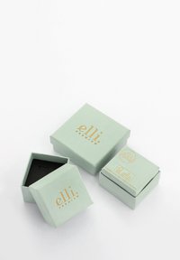 Două cutii de bijuterii verde mentă cu logo-uri aurii, una pătrată și cealaltă hexagonală, având o suprafață texturată și un interior negru.