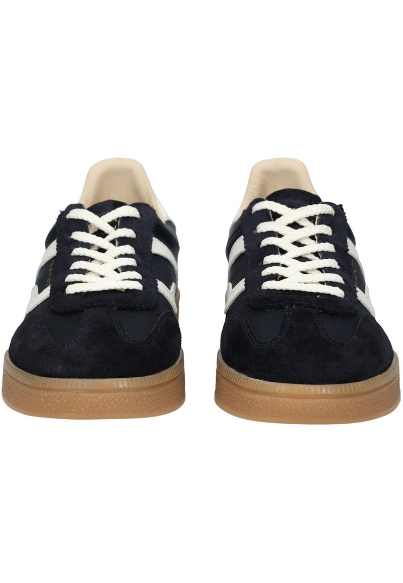 Granatowe trampki z zamszową cholewką, białymi sznurówkami i brązową gumową podeszwą. Posiadają dwa białe pasy po bokach oraz zaokrąglony czubek.