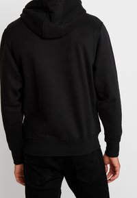 Schwarzer Hoodie aus Baumwollmischung, mit Kordelzugkapuze, gerippten Bündchen und einem leicht verkürzten Saum. Klassisches, minimalistisches Design.