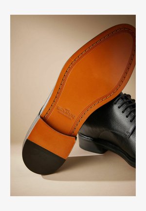 Must musta nahkking, millel on tekstureeritud ülemine osa, kontrastne pruun nahksool ja must konts. Omab nähtavaid õmblusi ja logo talla peal.